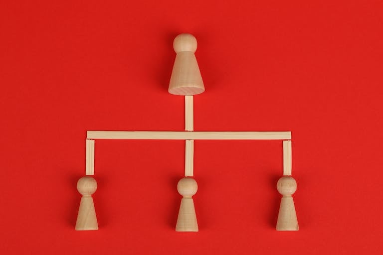 Conceptual depiction of hierarchy using wooden pieces on a vibrant red background.